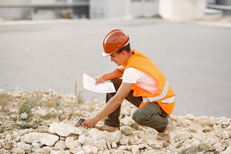 Engineer near the factory. Man in a helmet. Inspector looks at the building.
